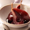 A quartered pear poached in red wine in a dessert bowl.